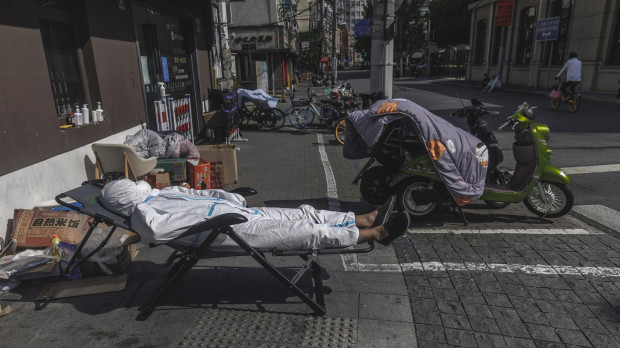 Un repartidor con equipo de protección duerme la siesta en la calle en medio del confinamiento