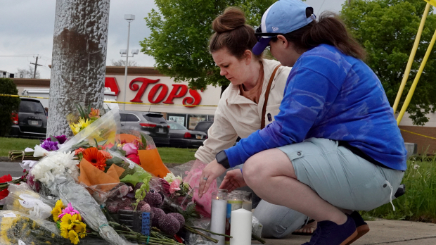 Las personas llevan flores en el lugar del tiroteo que dejó 10 personas muertas en Buffalo, Nueva York