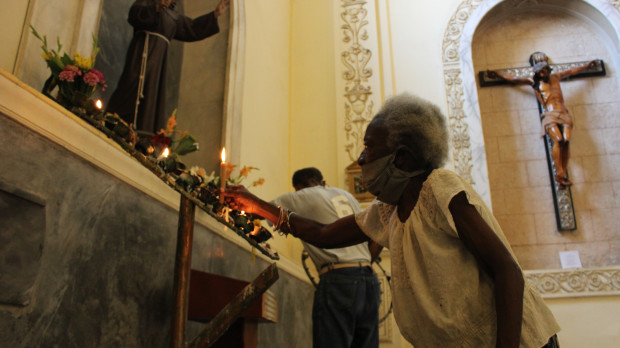 Una mujer cubana pone una vela ante la imagen de san Francisco de Asís, en una iglesia de La Habana