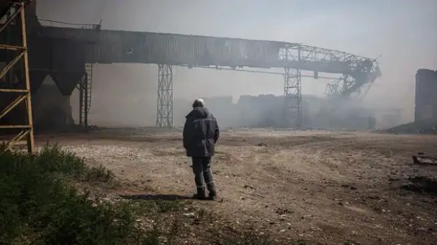 Un hombre observa como se eleva el humo de unos silos calcinados
