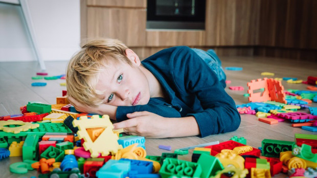 Niño triste con juguetes al rededor