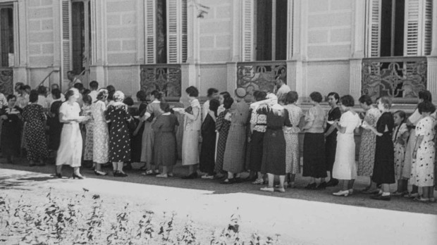 Grupo de personas esperando turno para obtener un plato de comida en los jardines de la embajada alemana de Madrid. Año 1936
