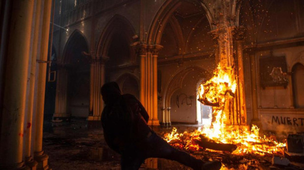 Un manifestante prende fuego dentro de la iglesia de San Francisco de Borja durante enfrentamientos con la policía antidisturbios en la conmemoración del primer aniversario del levantamiento social en Chile