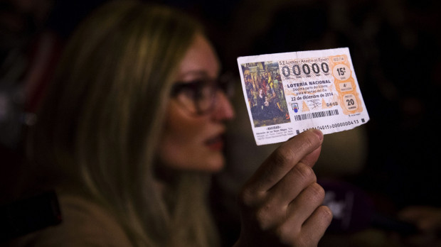 Una mujer muestra su décimo premiado con el número 00000 en 2014