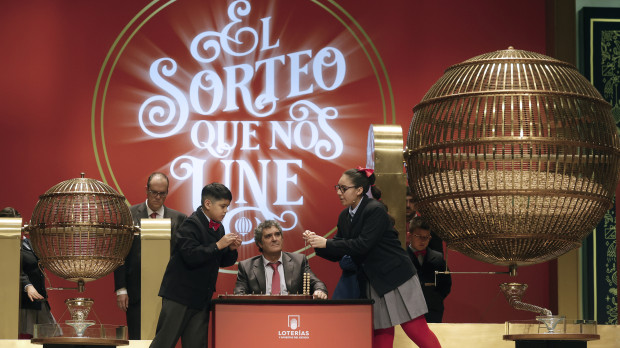Luis Alcides Paniagua (i) canta los números mientras su compañera Kiara Román Benitez (d) canta premios durante el sorteo de El Gordo de Navidad en el Teatro Real en Madrid, este jueves. EFE/ Javier Lizón