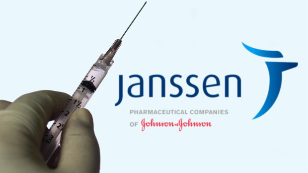 Una mano sujeta una vacuna con el logo de la compañía farmacéutica Janssen en el fondo