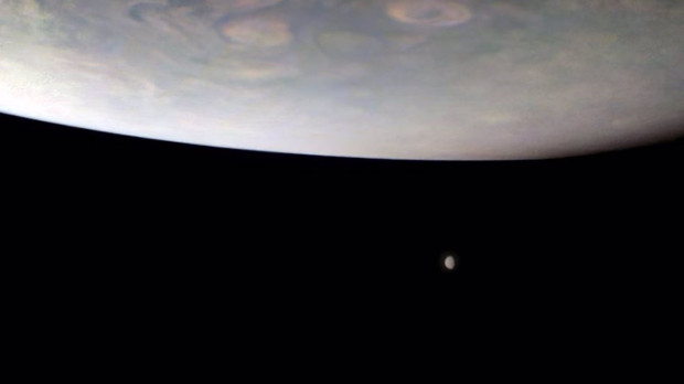 Imagen captada por la sonda Juno de dos grandes lunas en la lejanía debajo de Júpiter