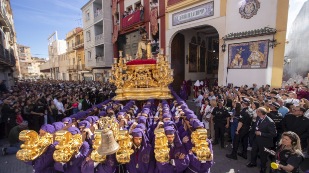 MÁLAGA, 03/04/2023.-Hombres de trono portan el Cristo de los Gitanos, hoy Lunes Santo en Málaga, en una procesión que destaca por ser la única de Málaga cuyos nazarenos no llevan capirotes, sino un capillo morado sujetado con una corona de espinas y que cuenta con una de las comitivas más peculiares, ya que durante el recorrido se suceden los bailes y cantes de los gitanos tras los tronos. EFE/Jorge Zapata