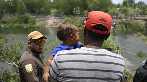 Migrants are given water by a member of the US military after they crossed into the United States from Mexico, in Brownsville, Texas, on May 11, 2023. - The US on May 11, 2023, will officially end its 40-month Covid-19 emergency, also discarding the Title 42 law, a tool that has been used to prevent millions of migrants from entering the country. (Photo by Andrew CABALLERO-REYNOLDS / AFP)