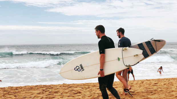 Dos jóvenes en la playa con sus tablas de surf