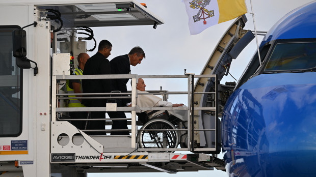 Pope Francis, seated on a wheelchair boards his plane on August 2, 2023 at Rome's Fiumicino airport, heading to the World Youth Day in Lisbon where a million youngsters from across the world are expected. (Photo by Andreas SOLARO / AFP)