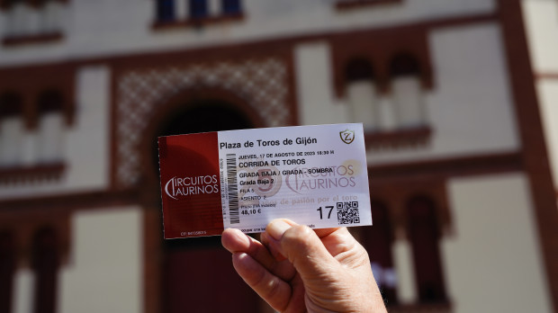 Un aficionado taurino muestra su entrada para uno de los días de la Feria de Begoña ante el coso El Bibio de Gijón. La plaza de toros de El Bibio recupera la Feria de Begoña tras un paréntesis de un año por la cancelación de un evento ahora retomado por el equipo de gobierno municipal de Foro, PP y Vox