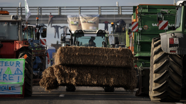 Un agricultor conduce un tractor cargado con bolas de heno durante un bloqueo de la autopista A64, en protesta contra los impuestos y la disminución de ingreso