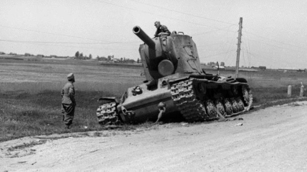 Un tanque soviético KV-2 abandonado al borde de la carretera inspeccionado por curiosos soldados alemanes