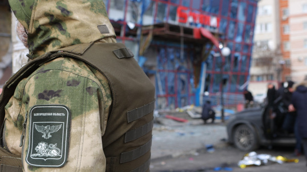 Una persona vestida con un traje de camuflaje es vista junto a un centro comercial dañado tras un ataque aéreo contra Belgorod