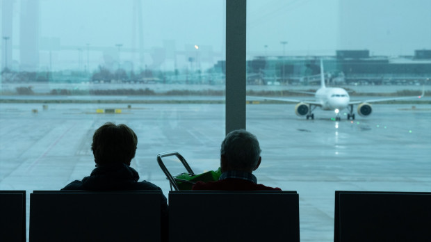 Dos personas esperan sentadas frente a un avión aparcado en la pista del aeropuerto de El Prat