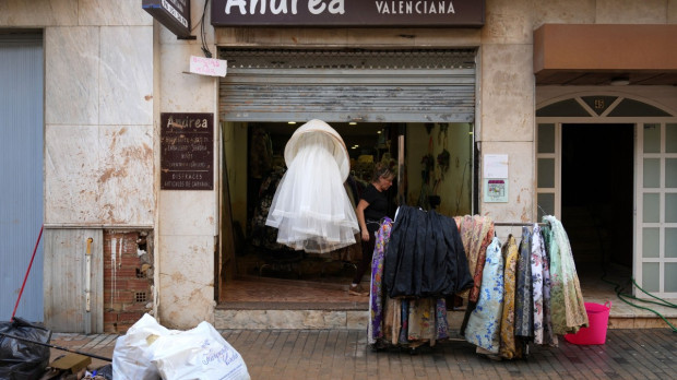 La dueña de una tienda de ropa cuelga su mercancía en la calle de Aldaia, al oeste de Valencia, tras las devastadoras inundaciones