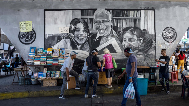 Un grupo de personas caminando frente a vendedores informales de libros en Caracas (Venezuela)