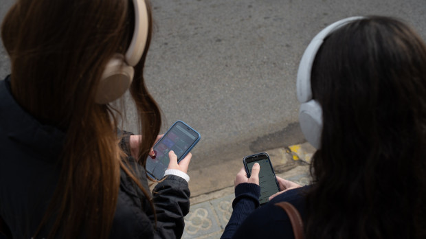 Dos jóvenes usan el teléfono móvil