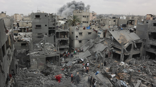 Rescatistas palestinos inspeccionan el lugar del bombardeo israelí contra un edificio residencial en el barrio de Shujaiyya, en la Ciudad de Gaza