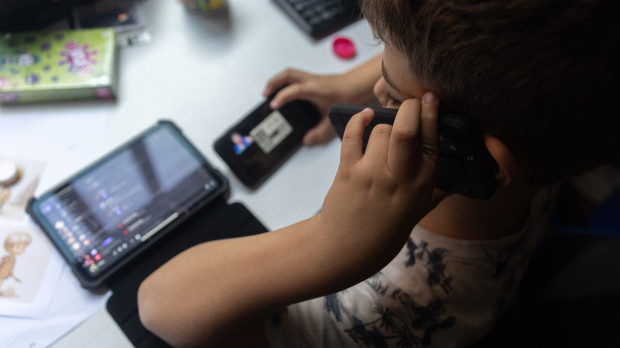 Un niño usa el teléfono móvil y una tablet