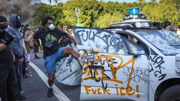 LOS ANGELES (United States), 08/06/2025.- A protester vandalizes a Waymo self driving car during immigration raid protests in Los Angeles, California, USA, 08 June 2025. US President Donald Trump has deployed 2,000 National Guard troops, despite not receiving a request from the state of California for any additional assistance, following large protests against ongoing immigration enforcement raids in the Los Angeles area over the last couple of days. (Protestas) EFE/EPA/ALLISON DINNER