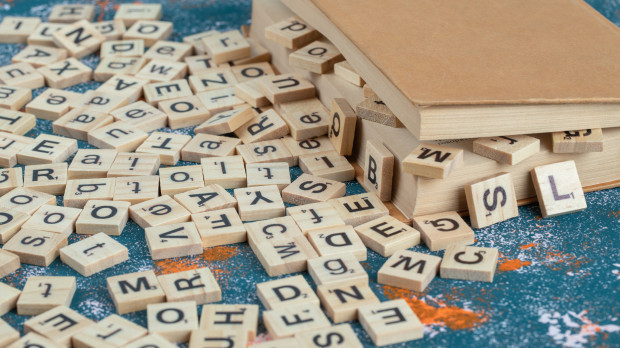 Wooden dice with letters on them between the pages of a book. High quality photo
