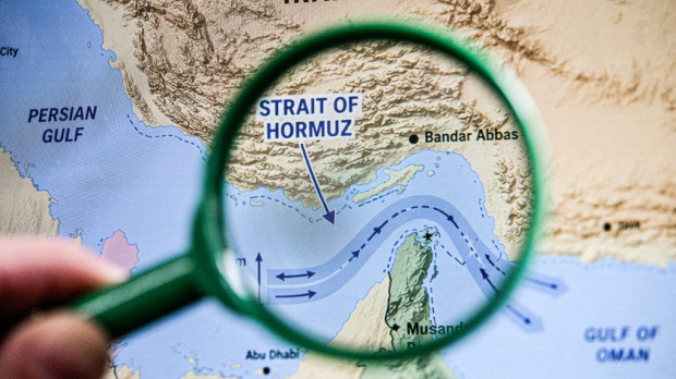 Primer plano de una lupa que resalta el estrecho de Ormuz en un mapa