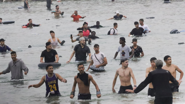 Un grupo de inmigrantes en la playa junto al paso fronterizo del Tarajal en Ceuta este viernes