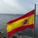 La bandera de España ondea en la isla de Alborán; al fondo, el buque de acción marítima Furor de la Armada española