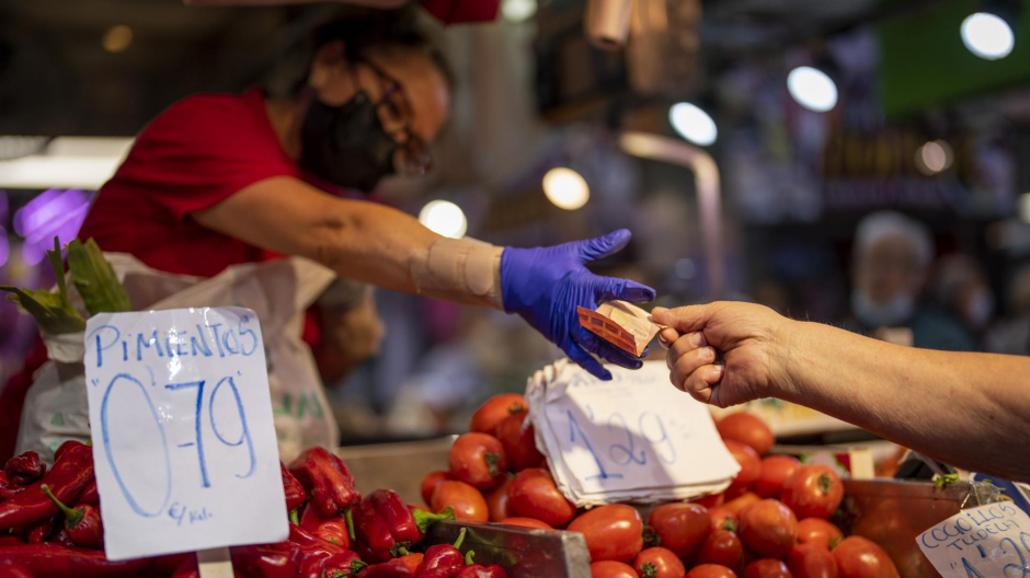 Un cliente paga su compra en un puesto de verdura en el mercado de Maravillas, en Madridfruteria