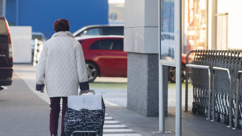 Una mujer sale de un supermercado con un carro de la compra en Mejorada del Campo, Madrid.