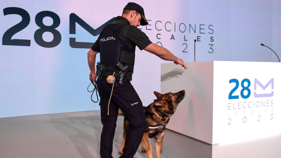 Un policía junto a su perro revisan las instalaciones de cara a la visita del ministro del Interior, Fernando Grande-Marlaska, a las instalaciones del Centro Nacional de Difusión de Datos Electorales del 28-M