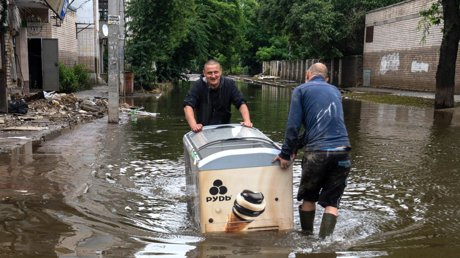 Dos residentes de Jersón empujan un congelador para helados a través del área inundada