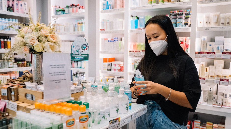 Una mujer con mascarilla mira un producto en una farmacia