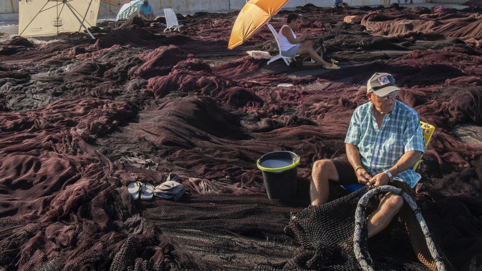 Unos pescadores arreglan artes de pesca en el muelle de Barbate, Cádiz.