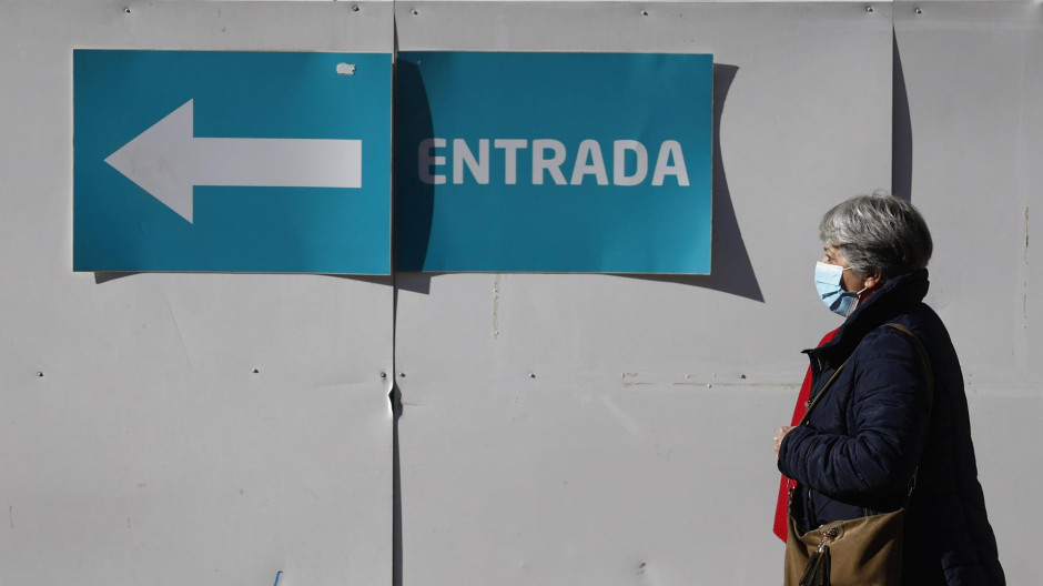 Una mujer con mascarilla camina en el entorno de un centro de salud