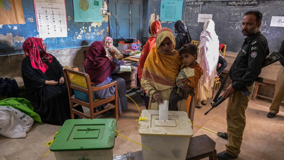 Una mujer que lleva un niño emite su voto en un colegio electoral durante las elecciones nacionales de Pakistán