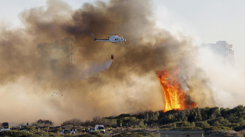 Un helicóptero trabaja en las labores de extinción del incendio forestal declarado a primera hora de la tarde de este lunes en El Saler, en Valencia
