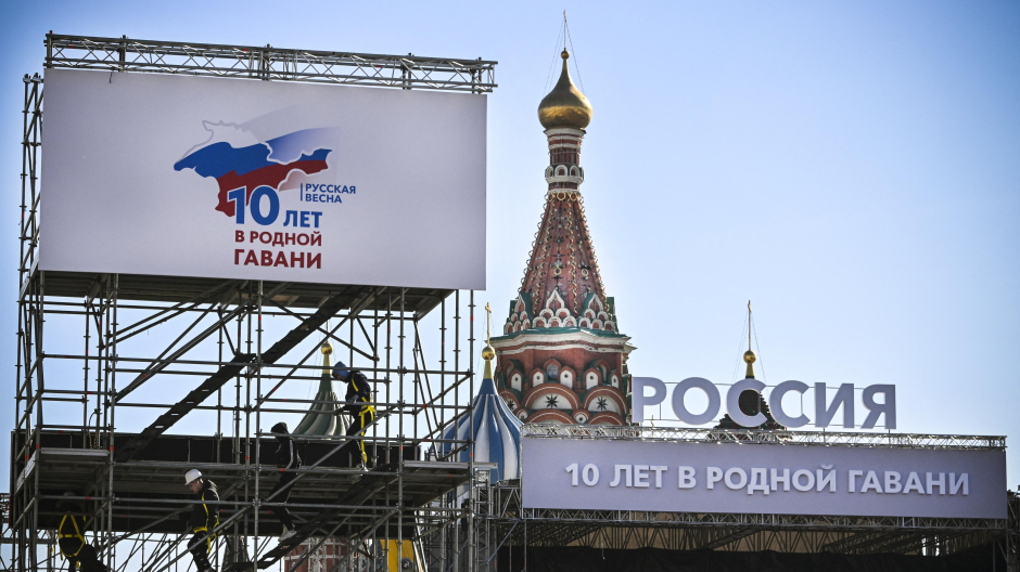 Los trabajadores suben a un escenario que marca el décimo aniversario de la anexión de Crimea por Rusia