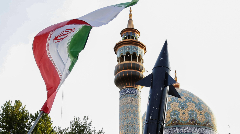 Los iraníes levantan una bandera y la maqueta de un misil durante una celebración tras el ataque con misiles y drones de Irán contra Israel, el 15 de abril de 2024, en la plaza Palestina en el centro de Teherán