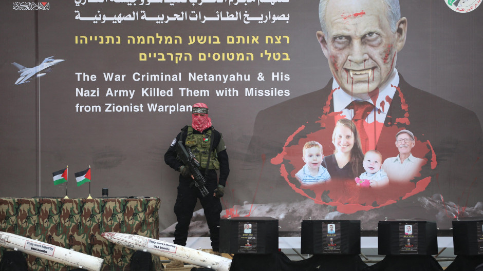 Un terrorista de Hamás escolta los cuatro ataúdes de los rehenes israelíes muertos en Gaza