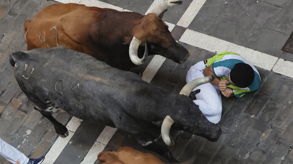Toros de la ganadería Cebada Gago pasan por encima de un mozo a su paso por la calle de la Estafeta
