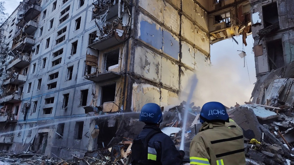 Los rescatistas usan una manguera para extinguir un incendio en un edificio residencial dañado después de un ataque en
