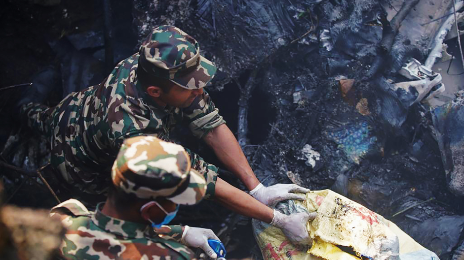 Un equipo de emergencias inspecciona el lugar donde el avión se ha estrellado en Nepal buscando supervivientes