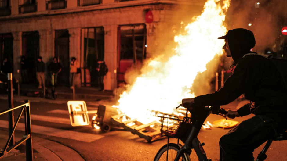 Un residente local monta su bicicleta frente a un incendio durante una manifestación en París, Francia