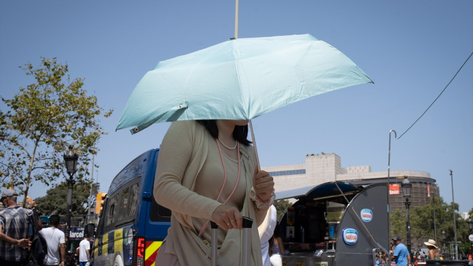 Una persona trata de protegerse del sol en Las Ramblas, Barcelona