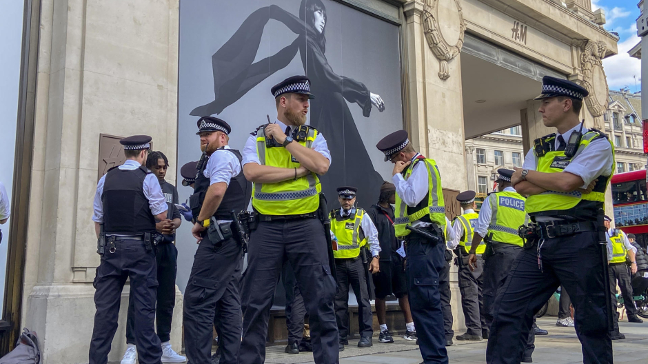 Agentes de policía registran a un joven a las puertas de una tienda de ropa en Londres