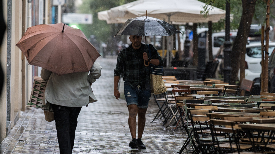 Varias personas se resguardan de la lluvia con paraguas