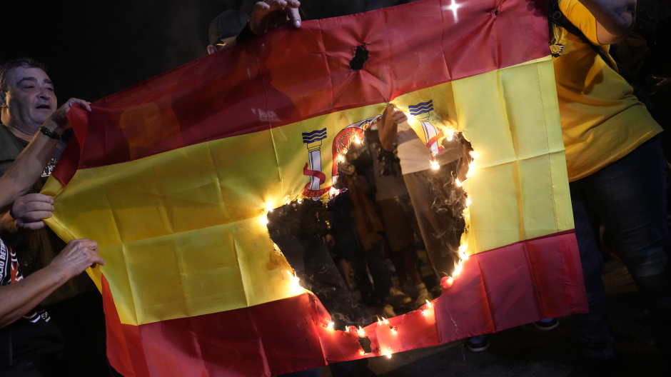 Bandera española ardiendo ante la Travessera de Gràcia de Barcelona